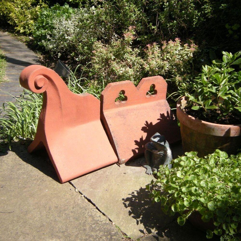 Small swan neck roof finial in the garden with a crested ridge tile