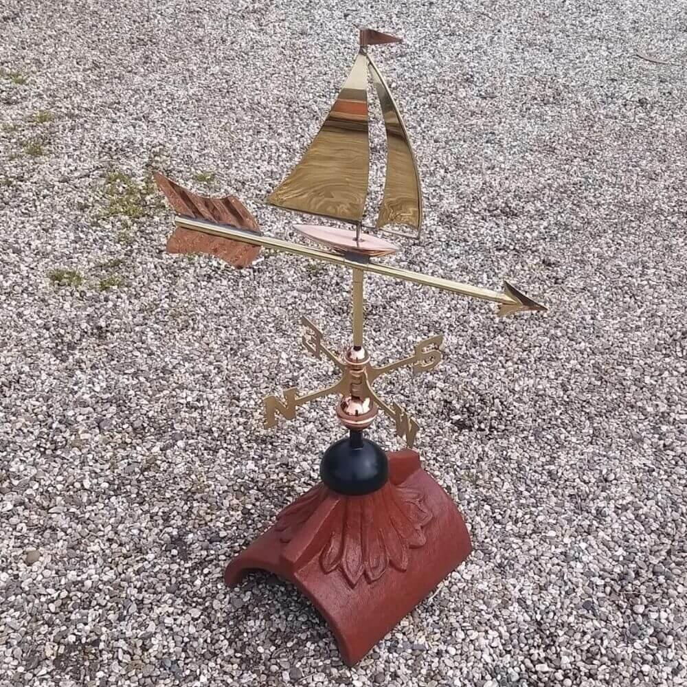 Decorative polished copper sailboat weathervane fitted to a square ridge tile