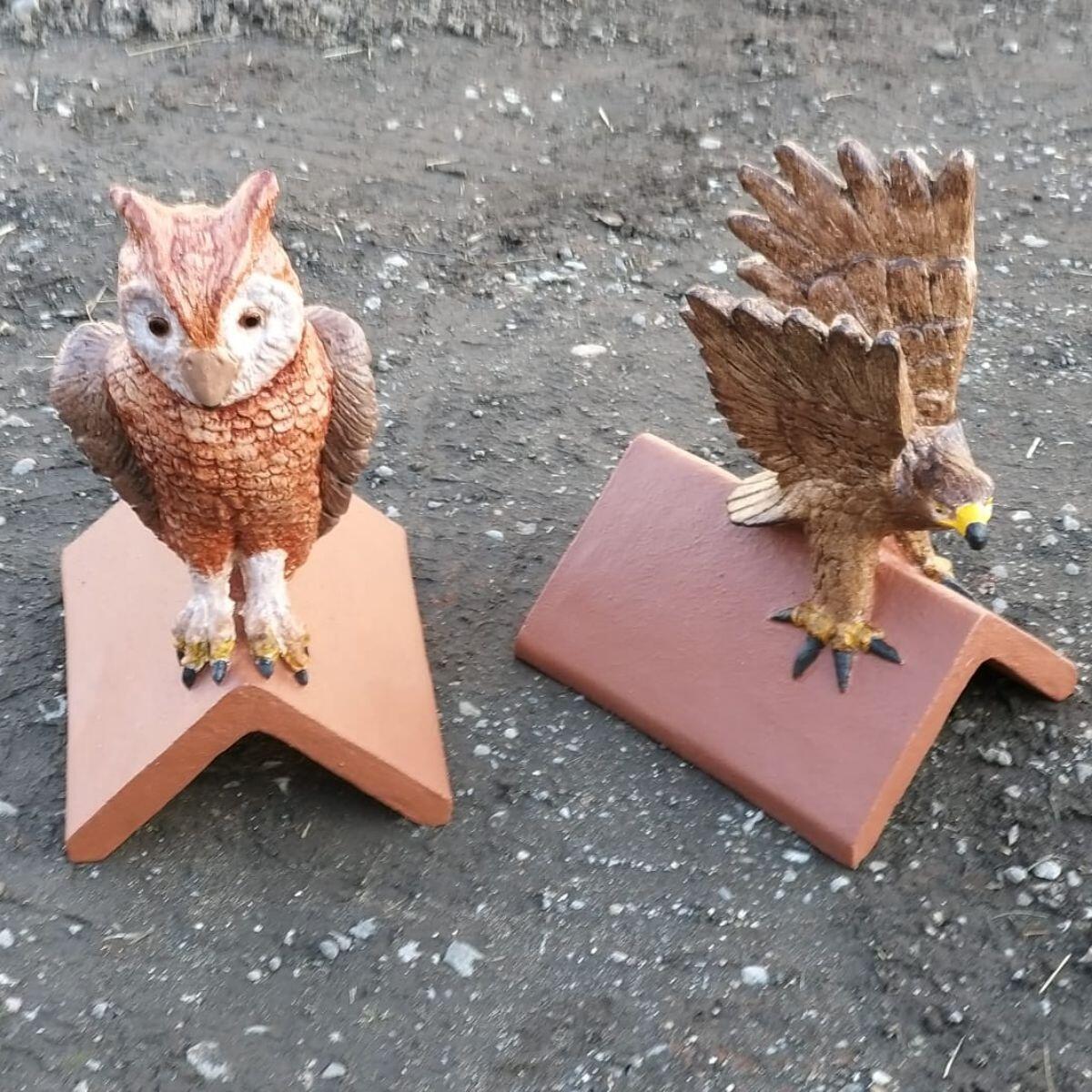 A pair of hand painted owl roof finials outside of the workshop