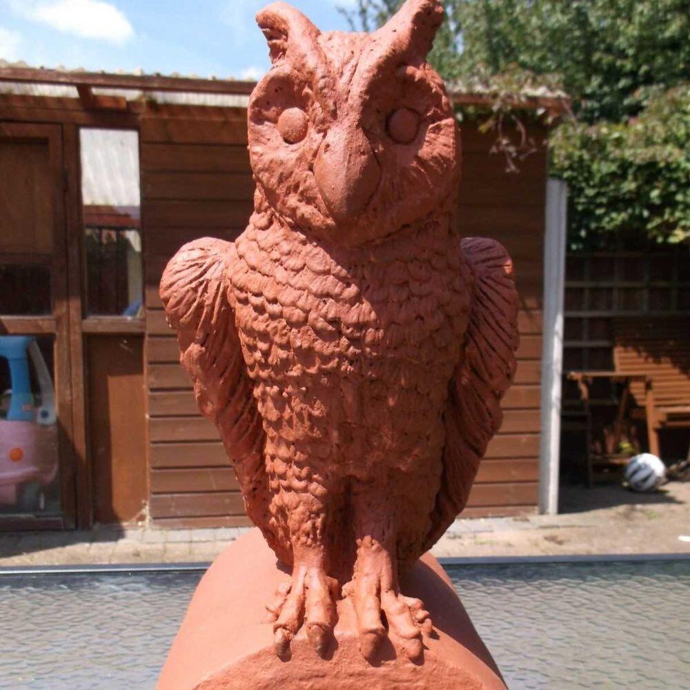 A terracotta owl roof finial stop end roof finial can be seen displayed in the garden